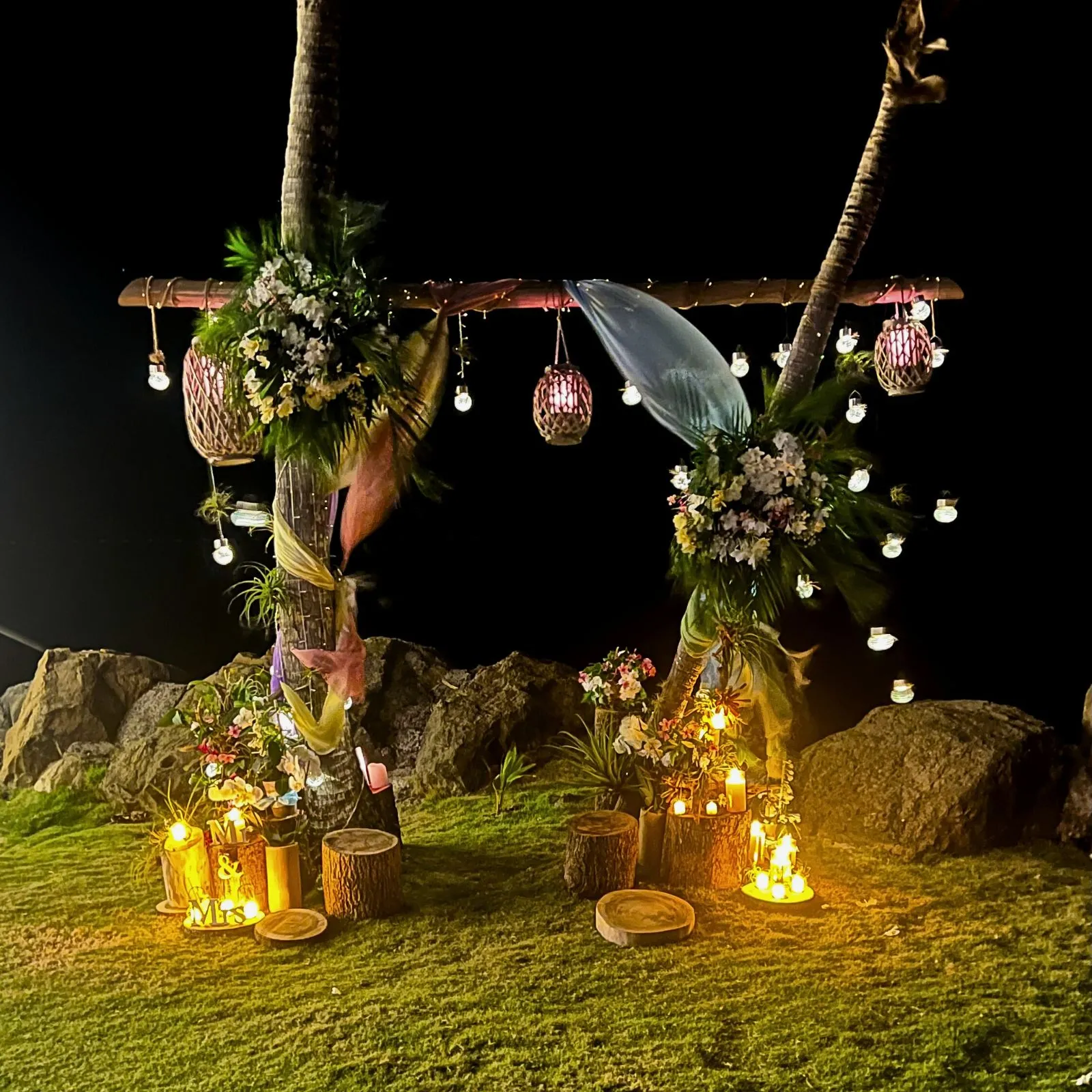 Arche de mariage en bord de mer éclairée la nuit avec fleurs tropicales en Martinique