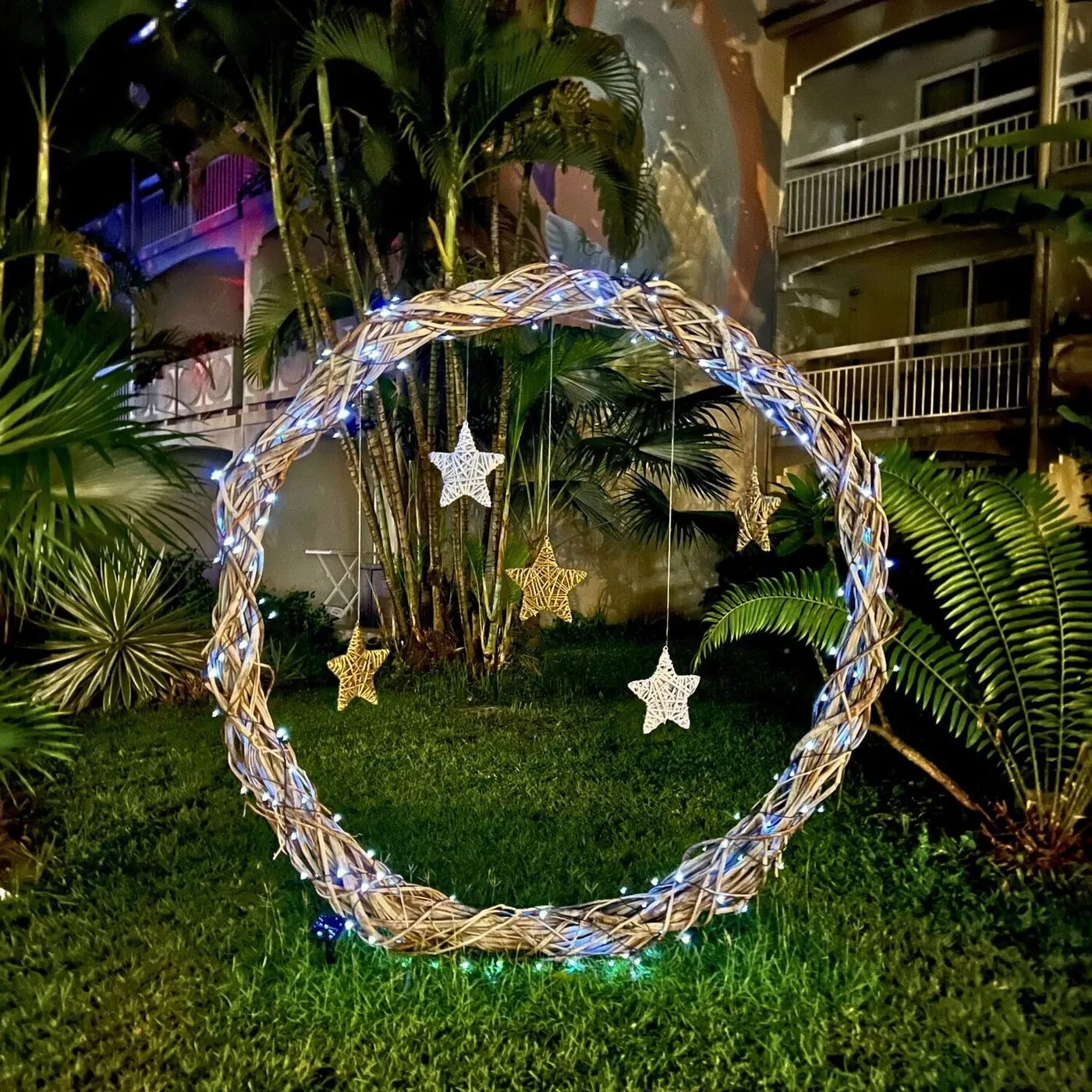 Arche ronde en liane tressée avec guirlande lumineuse et étoiles en rotin pour décoration de Noël en extérieur en Martinique