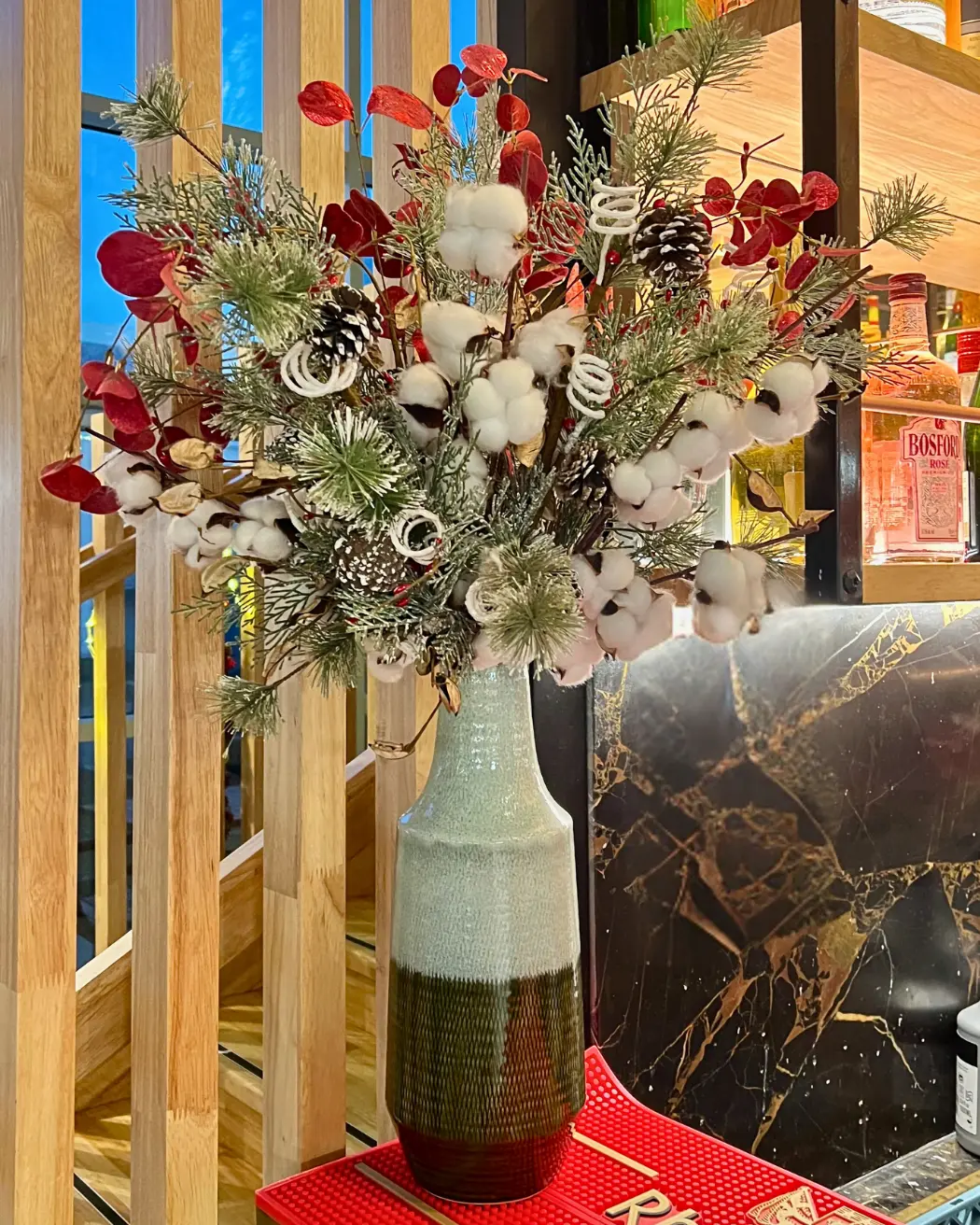 Bouquet de Noël avec coton, feuillages et éléments rouges dans vase pour décoration de restaurant en Martinique