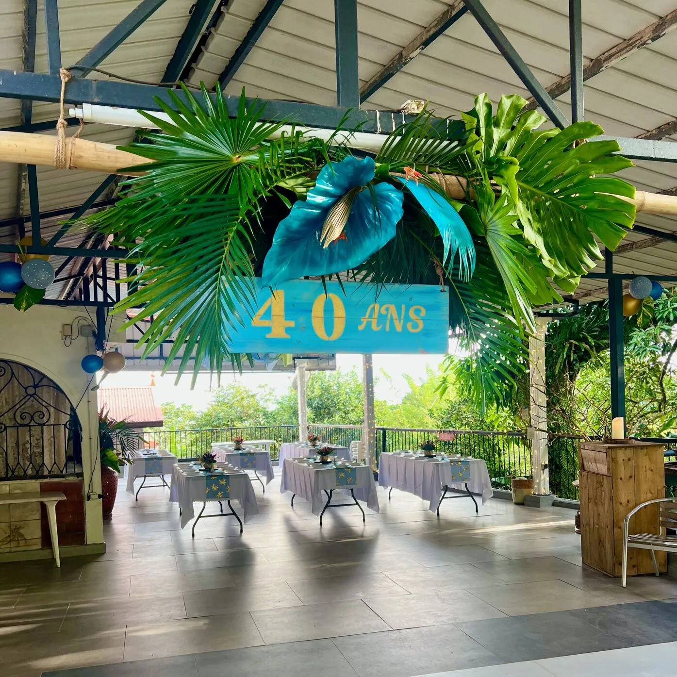 Décoration anniversaire Martinique : composition végétale suspendue sur bambou avec pancarte en bois personnalisée