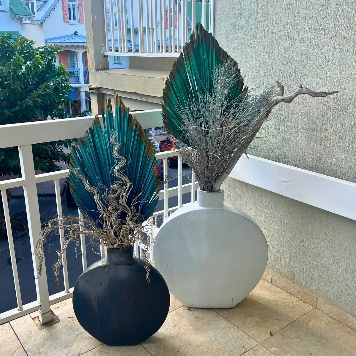 Composition végétale avec feuilles de palmier peintes en vert et bleu dans grands vases pour décoration d’hôtel en Martinique