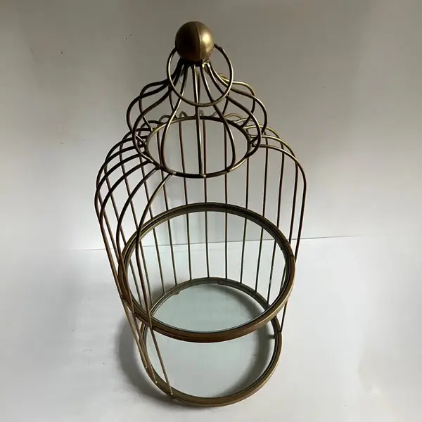 Cage dorée en métal avec plateaux en verre utilisée comme présentoir décoratif ou élément de scénographie d'évènement