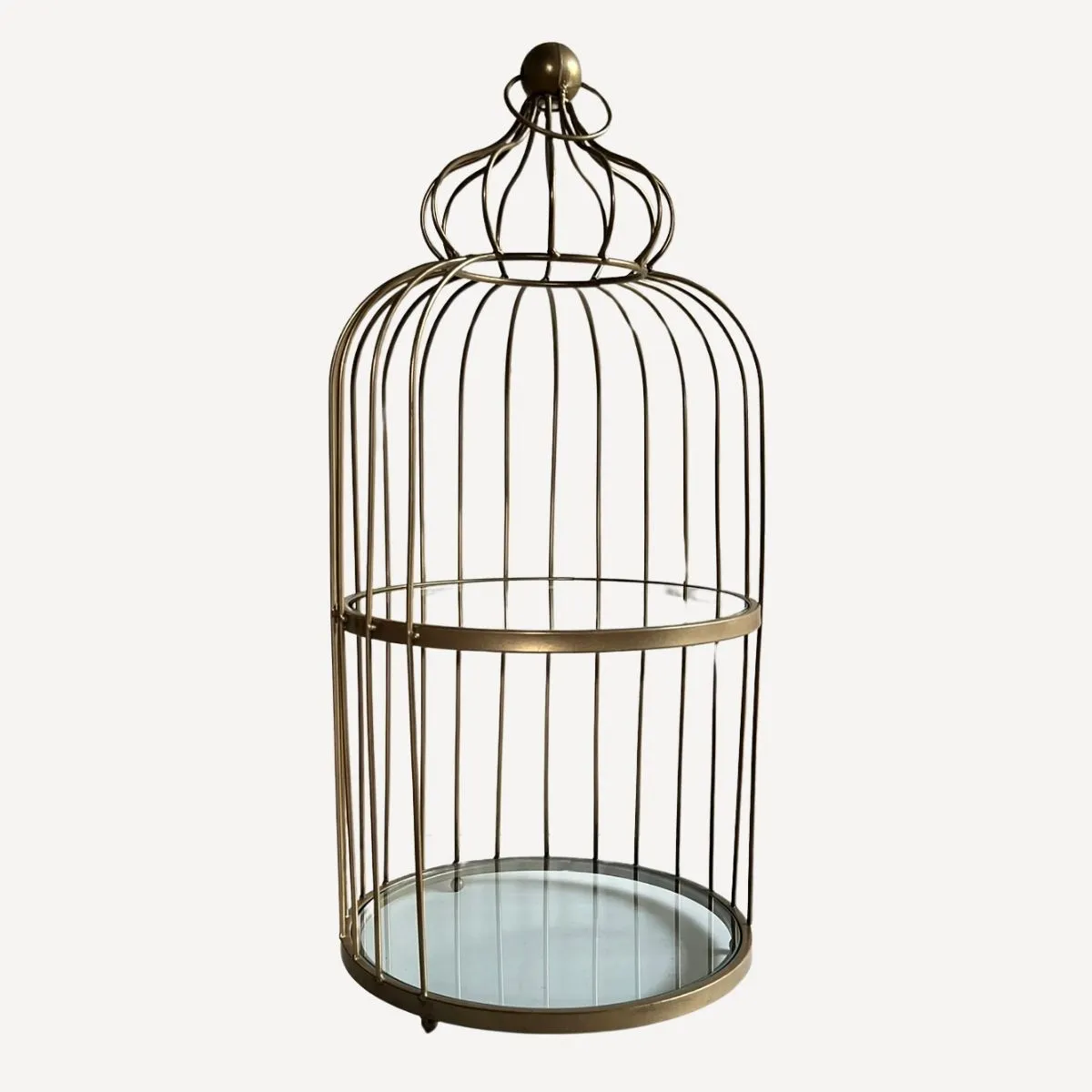 Cage dorée en métal avec plateaux en verre utilisée comme présentoir décoratif ou élément de scénographie d'événement