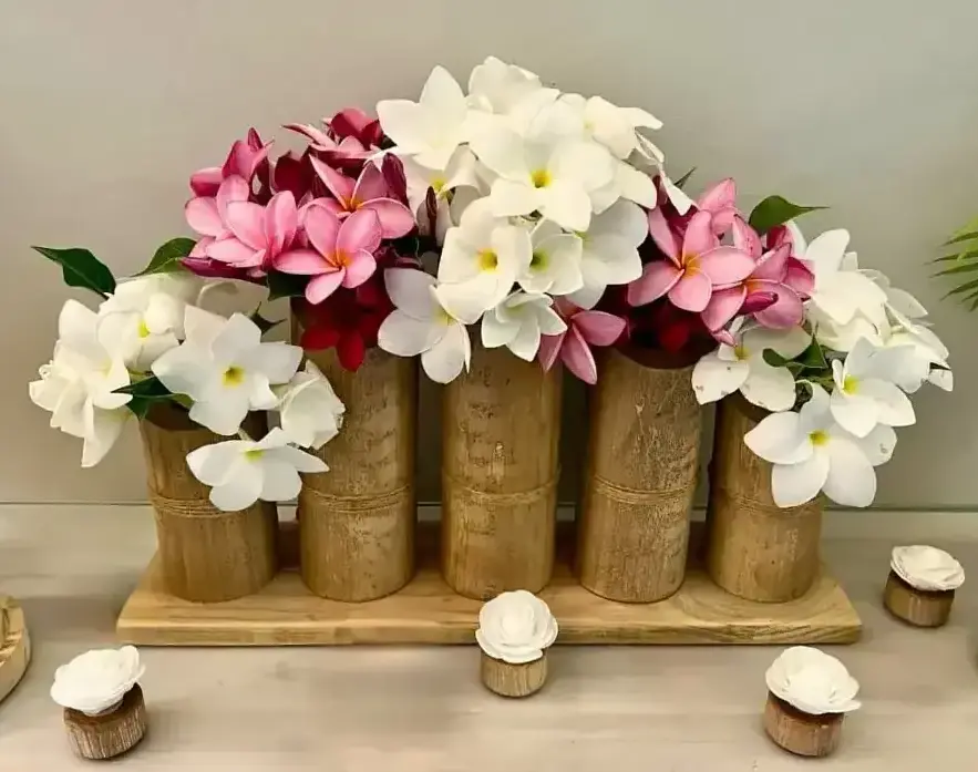 Vases en bambou sur socle en bois avec compositions florales pour décoration événementielle en Martinique