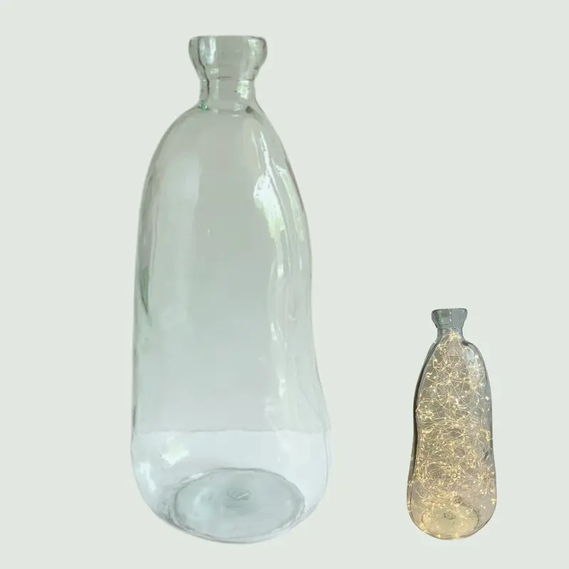 Dame-jeanne en verre transparent utilisée comme vase ou luminaire décoratif lors d'événements