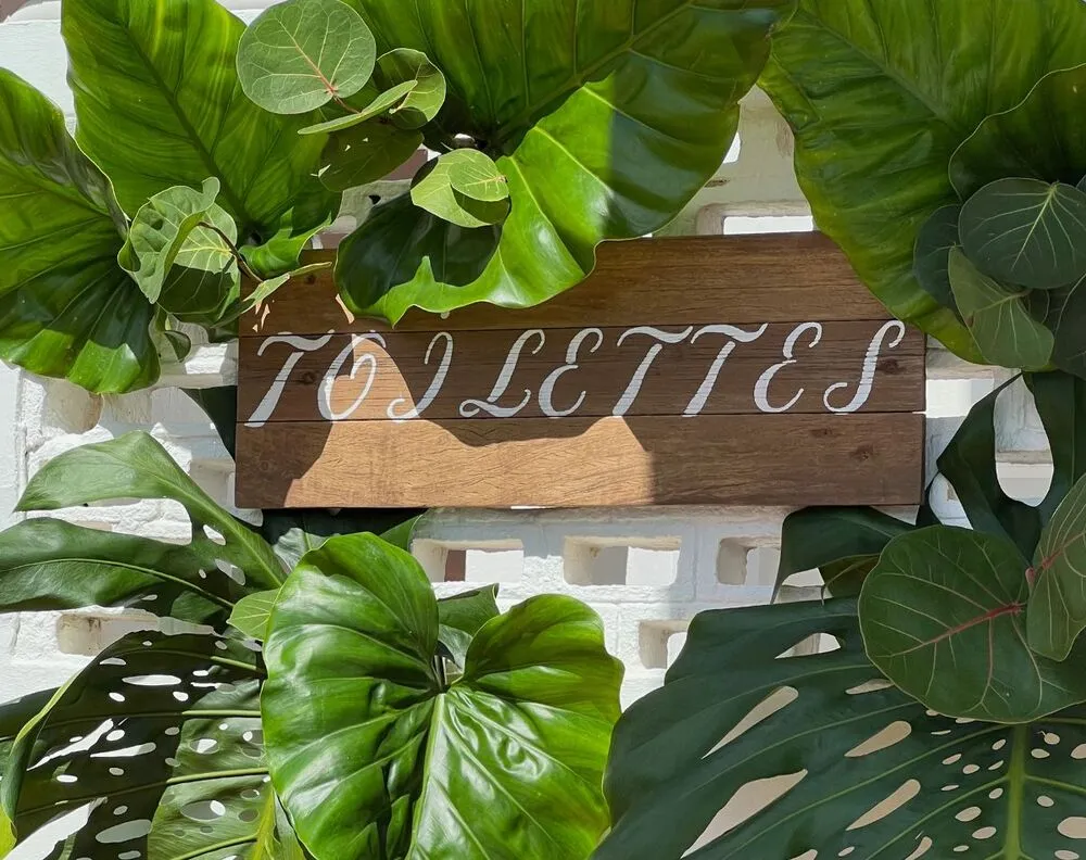 Panneau signalétique en bois ancien avec lettrage manuscrit et feuillage pour événement en Martinique